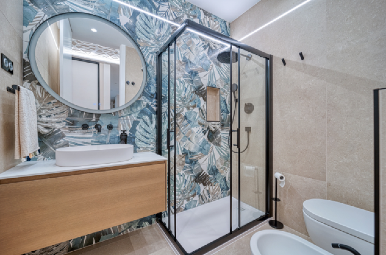 Baño reformado con revestimiento botánico, madera natural y mampara negra