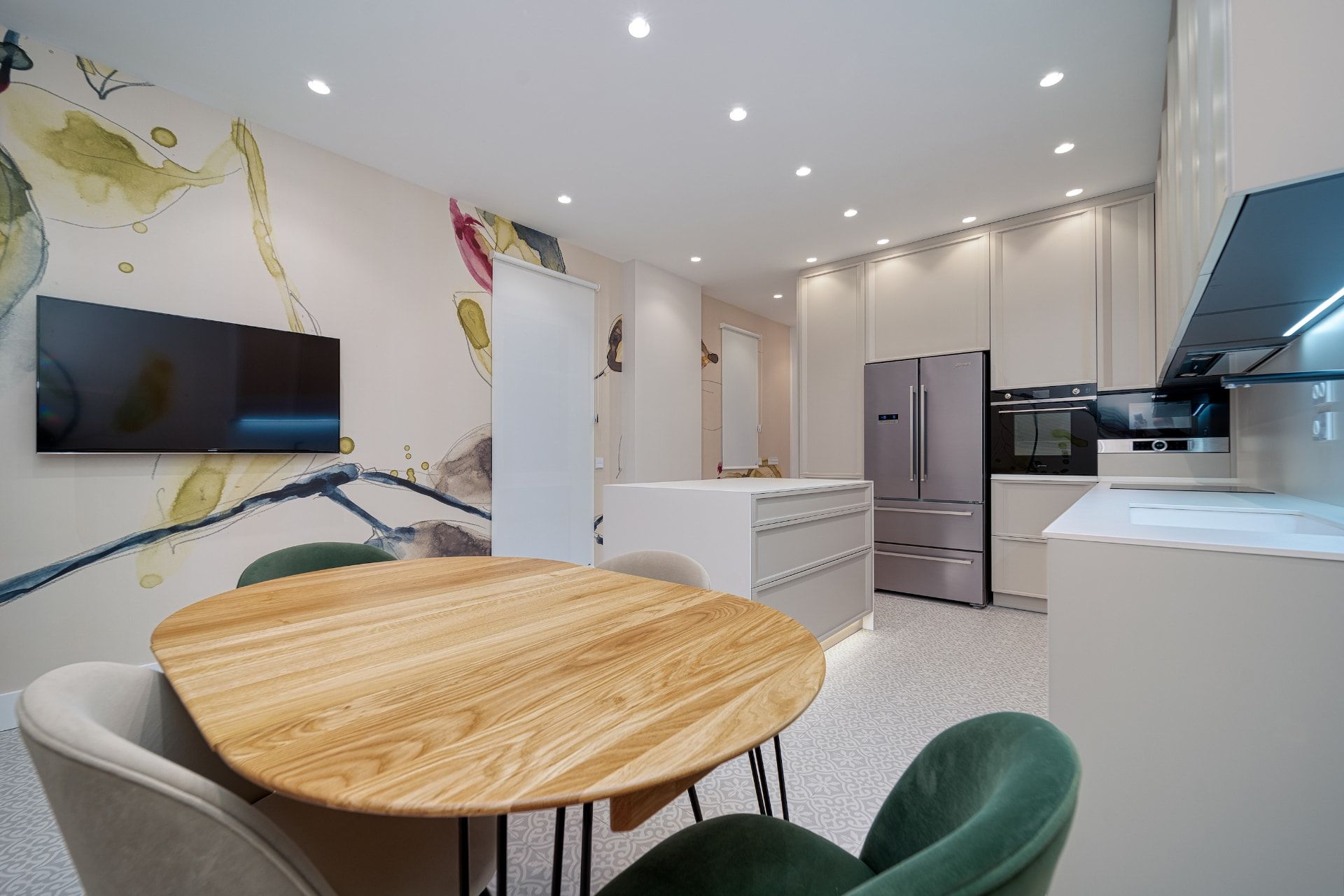 Cocina-comedor integrada en Barrio de Salamanca con mobiliario blanco, mesa de madera y paneles decorativos