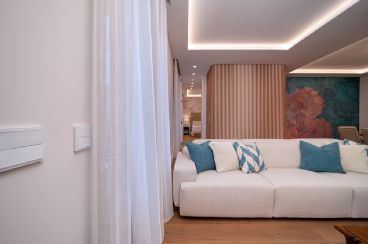 Salón reformado con iluminación indirecta, sofá blanco y revestimiento de madera
